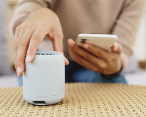 close-up on hand using phone connecting speaker bluetooth